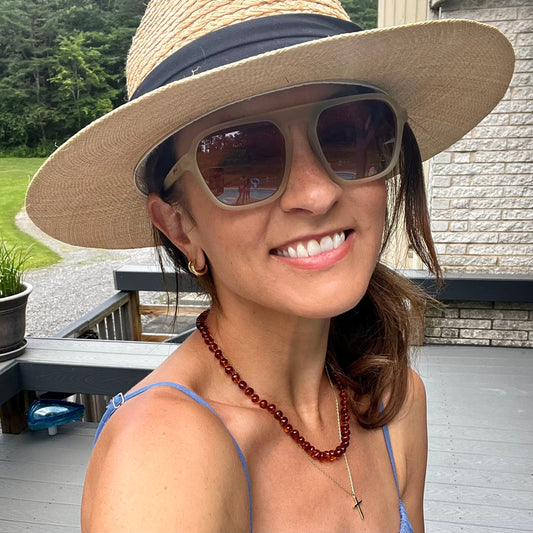 adult woman wearing cognac baltic amber necklace with a hat