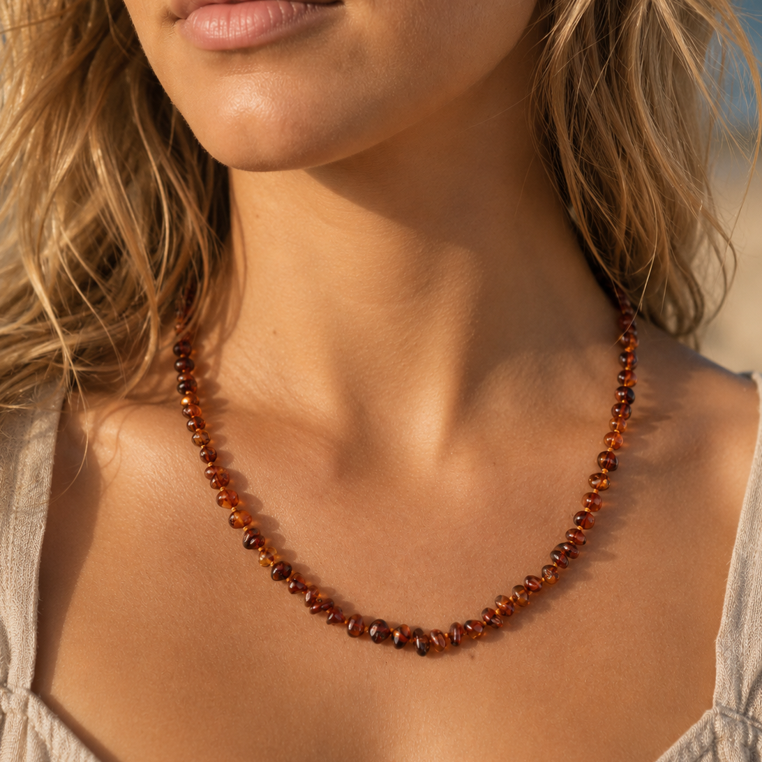 Close-up of a woman wearing a cognac brown baltic amber beaded necklace with a blurred background